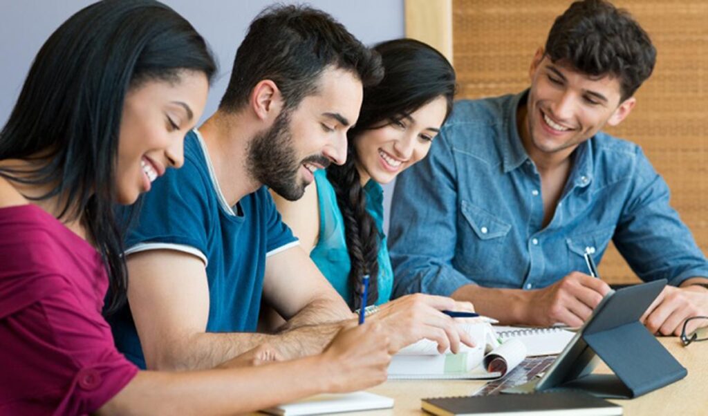 A group of diverse young students studying together with books and a tablet, smiling and engaged in learning—reflecting HIDM's beginner-friendly curriculum in digital marketing, SEO, social media marketing, and Google Ads training.