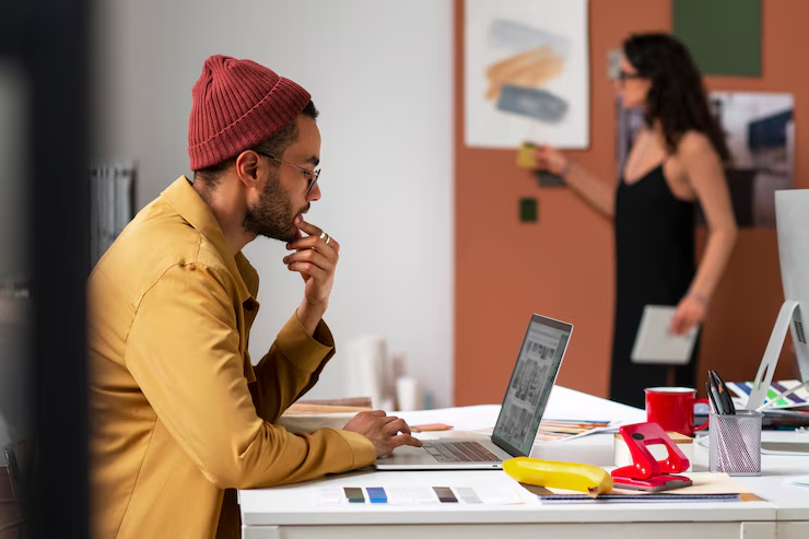 "Freelancer and entrepreneur from HiDM working on a laptop in a creative workspace, analyzing digital projects and building online business strategies."