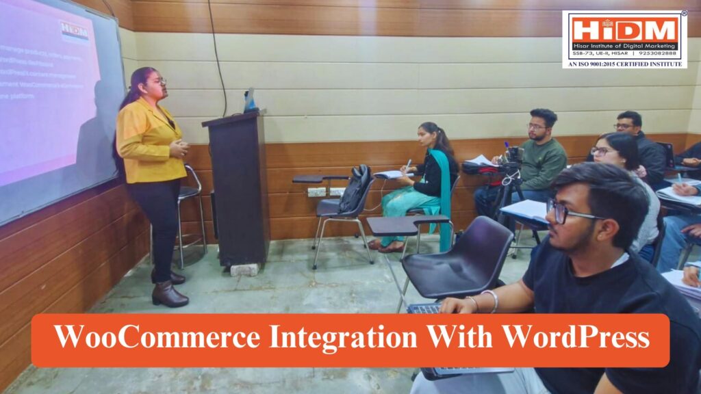A classroom session at HiDM (Hisar Institute of Digital Marketing) where a female presenter is delivering a seminar on WooCommerce integration with WordPress. Students are seated attentively with notebooks and laptops while a presentation is displayed on a projector screen. The image includes HiDM branding and a banner reading "WooCommerce Integration With WordPress."