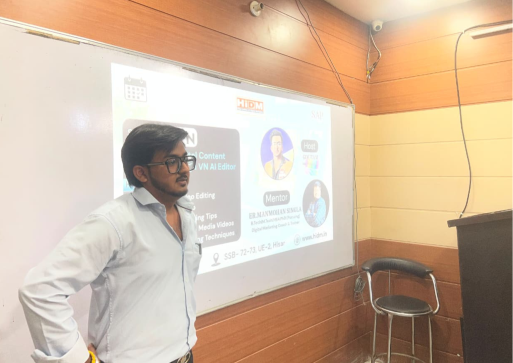 Goutam interacting with students during the VN AI Editor seminar while standing beside the presentation screen at HiDM.