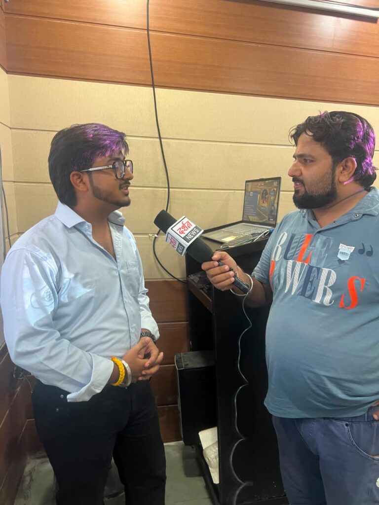 Goutam being interviewed by a news reporter after conducting the VN AI Editor seminar at HiDM. He is answering questions while standing near the presentation setup with a laptop in the seminar hall.
