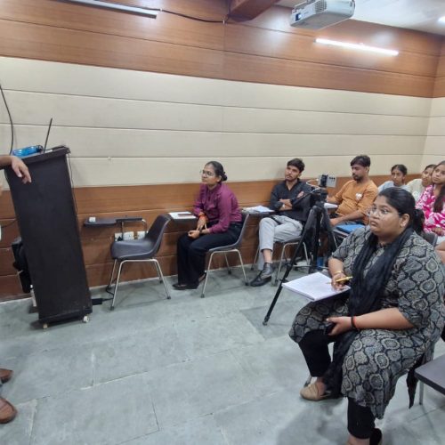 Ishaan, an HIDM student, delivering a seminar presentation on AI tools used in market research while standing beside a projected slide titled “Top AI Tools Used in Market Research.”