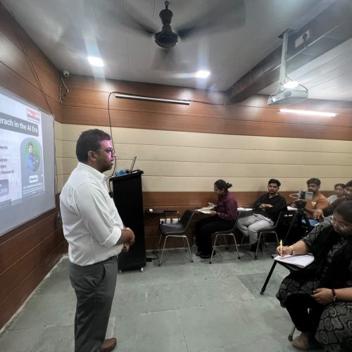 Ishaan, an HIDM student, delivering a seminar presentation on AI tools used in market research while standing beside a projected slide titled “Top AI Tools Used in Market Research.”